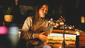 Ukulele spielende und singende Frau als Beispiel für ein Instrument mit U.
